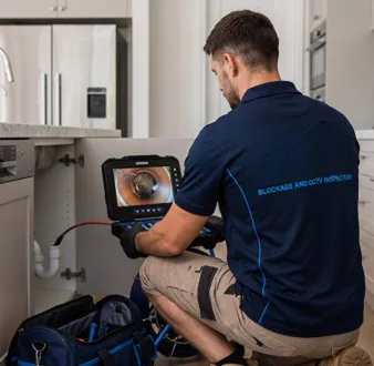 Plumber clearing a blocked toilet in a Oakville bathroom